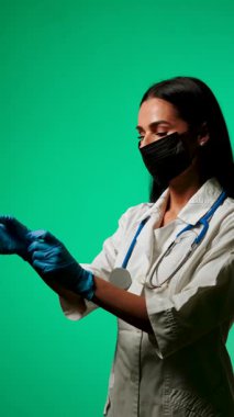 Klinik ortamda yeşil bir zemine karşı maske ve steteskop takan sağlık uzmanı