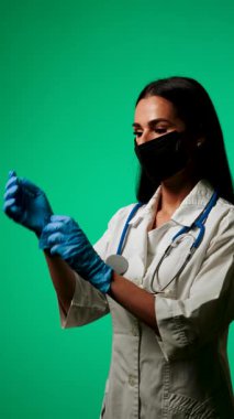 Klinik ortamda yeşil bir zemine karşı maske ve steteskop takan sağlık uzmanı