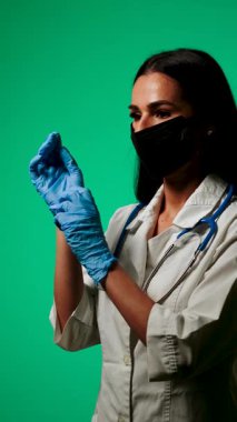 Klinik ortamda yeşil bir zemine karşı maske ve steteskop takan sağlık uzmanı