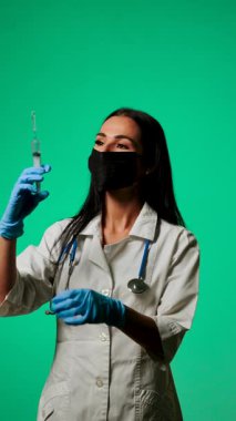 Klinik ortamda yeşil bir zemine karşı maske ve steteskop takan sağlık uzmanı