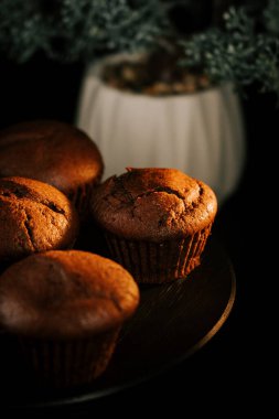 Mükemmel pişirilmiş lezzetli çikolatalı kekler yumuşak ışıkta, karanlık bir tabakta dinleniyor.