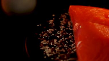 Baharatlı alabalık filetosu canlı renkler ve dokular içeren siyah bir yüzey üzerinde döner