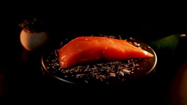 Baharatlı alabalık filetosu canlı renkler ve dokular içeren siyah bir yüzey üzerinde döner