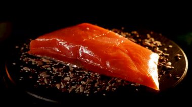 Baharatlı alabalık filetosu canlı renkler ve dokular içeren siyah bir yüzey üzerinde döner