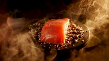 Baharatlı alabalık filetosu canlı renkler ve dokular içeren siyah bir yüzey üzerinde döner