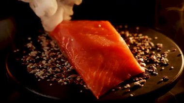 Baharatlı alabalık filetosu canlı renkler ve dokular içeren siyah bir yüzey üzerinde döner