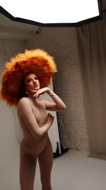 Moda modeli, modern bir stüdyo ortamında yaratıcı ve stil gösteren canlı sarı bir şapka takıyor.