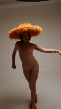 Moda modeli, modern bir stüdyo ortamında yaratıcı ve stil gösteren canlı sarı bir şapka takıyor.