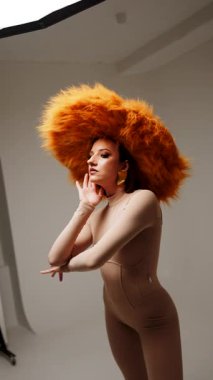 Moda modeli, modern bir stüdyo ortamında yaratıcı ve stil gösteren canlı sarı bir şapka takıyor.