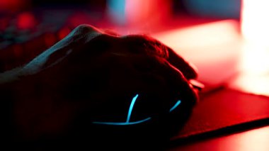 Gece vakti loş bir oyun ayarında oyun faresi kullanan bir elin yakın plan görüntüsü
