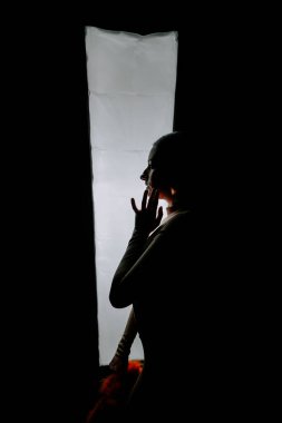 Model, yaratıcı bir moda çekimi sırasında minimalist bir stüdyoda canlı turuncu şapkayla dramatik bir şekilde poz verir.