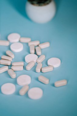Türkuaz bir yüzeye saçılmış çeşitli hap ve tabletler.