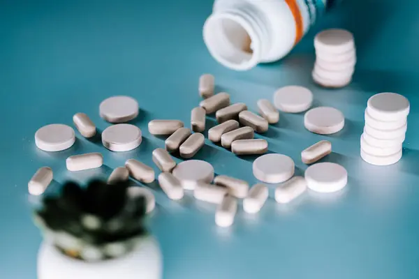 Haplar küçük bir bitkinin yanındaki masaya saçılmış ve kapalı bir yerde açık bir ilaç şişesi var.