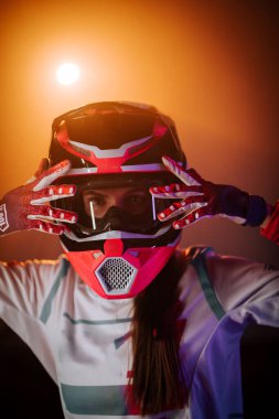 Miğferli bir kadın motosikletçinin portresi. Gece parlak neon ışıklarıyla aydınlatılıyor.