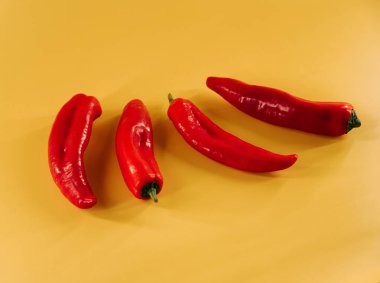 Kırmızı biberler canlı sarı arkaplanda mutfak vitrininde sergileniyor.