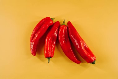 Kırmızı biberler canlı sarı arkaplanda mutfak vitrininde sergileniyor.