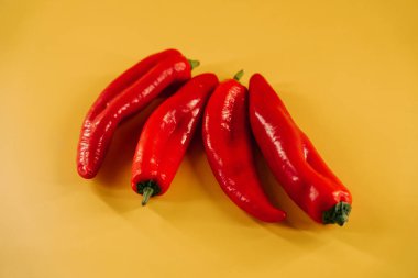 Kırmızı biberler canlı sarı arkaplanda mutfak vitrininde sergileniyor.