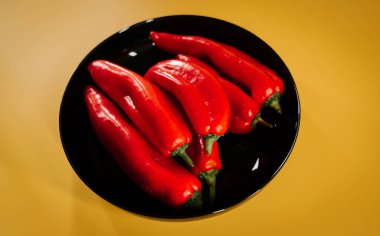 Kırmızı biberler canlı sarı arkaplanda mutfak vitrininde sergileniyor.