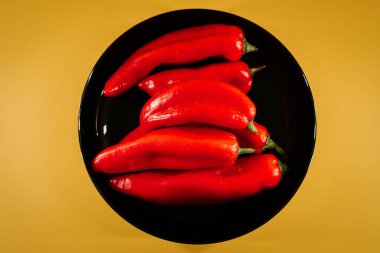 Kırmızı biberler canlı sarı arkaplanda mutfak vitrininde sergileniyor.