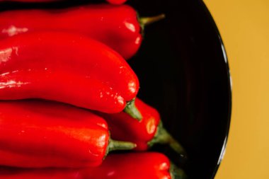 Kırmızı biberler canlı sarı arkaplanda mutfak vitrininde sergileniyor.