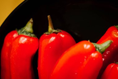 Kırmızı biberler canlı sarı arkaplanda mutfak vitrininde sergileniyor.