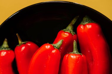 Kırmızı biberler canlı sarı arkaplanda mutfak vitrininde sergileniyor.