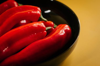 Kırmızı biberler canlı sarı arkaplanda mutfak vitrininde sergileniyor.