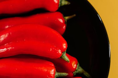 Kırmızı biberler canlı sarı arkaplanda mutfak vitrininde sergileniyor.