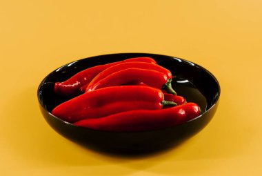 Kırmızı biberler canlı sarı arkaplanda mutfak vitrininde sergileniyor.