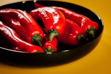 Kırmızı biberler canlı sarı arkaplanda mutfak vitrininde sergileniyor.