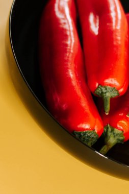 Kırmızı biberler canlı sarı arkaplanda mutfak vitrininde sergileniyor.