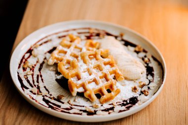 Muz dilimleri ve çikolata sosuyla servis edilen lezzetli Belçika waffleları.