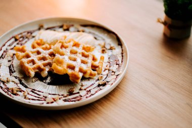 Lezzetli Belçika waffleları, meyve sosu ve fındıklı dekoratif bir tabakta servis edilir.