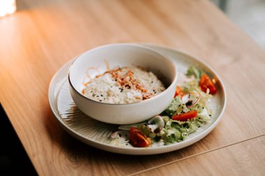 Taze salatanın yanında kıtır kıtır yulaf ezmesi ve rendelenmiş parmesan.