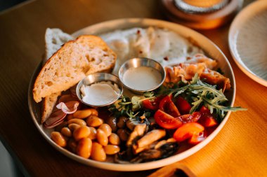 Taze malzeme ve ahşap bir masada zanaat ekmeği bulunan gurme şarküteri tabağı.