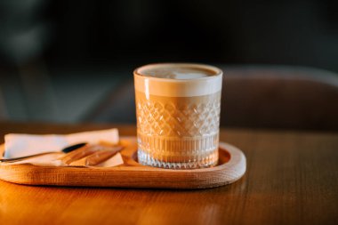 Sıcak latte, rahat bir kafe ortamında ahşap bir masada kurabiyelerle servis edilir.