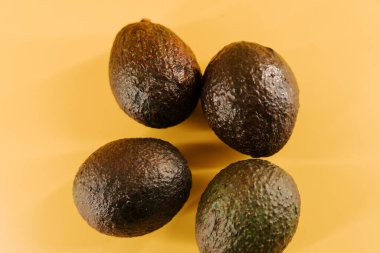 Canlı bir besin sunumu için parlak sarı bir yüzeyde taze avokadolar sergileniyor.