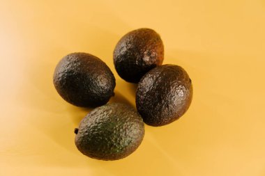 Canlı bir besin sunumu için parlak sarı bir yüzeyde taze avokadolar sergileniyor.