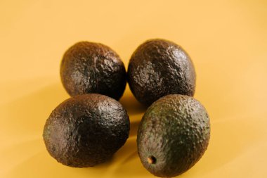 Canlı bir besin sunumu için parlak sarı bir yüzeyde taze avokadolar sergileniyor.