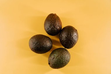 Canlı bir besin sunumu için parlak sarı bir yüzeyde taze avokadolar sergileniyor.