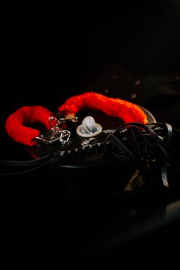 Karanlık bir yüzeyde parlak renkli kelepçeler ve deri kayışlar ilginç bir natürmort oluşturur.