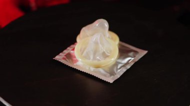 Yaratıcı görsel görüntü için kırmızı ışık efektleriyle siyah bir yüzey üzerinde dönen prezervatifler