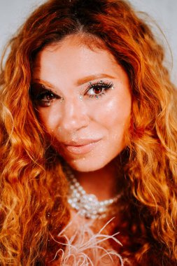 Moda portresi, temiz beyaz arka planda kızıl saçlı bir kadını gösteriyor.