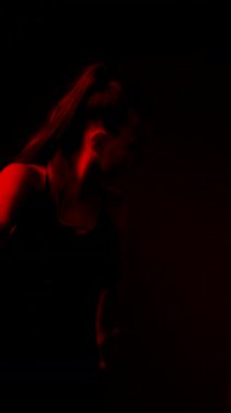 Kadın jimnastikçi, neon ışıklı ekranda kurdeleyle ritmik jimnastik yapıyor.