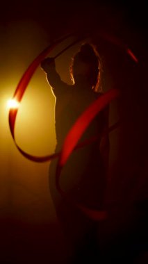 Kadın jimnastikçi canlı neon ışıklarıyla ritmik bir gösteri sergiliyor.