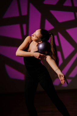 Kadın renkli bir arka planda çemberle ritmik jimnastik yapıyor.