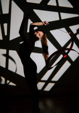 Kadın, sanatsal performansta kurdeleli ritmik jimnastik becerileri sergiliyor