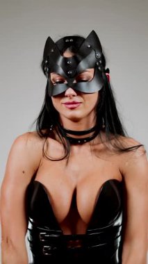 BDSM kedi maskesi modeli stüdyo ortamında deri korse içinde poz verir