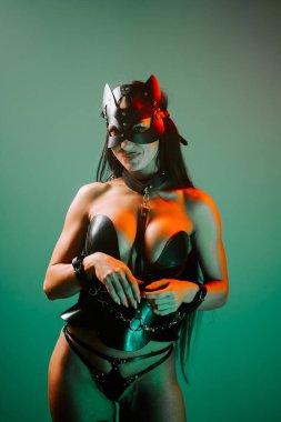 Kedi maskeli ve kelepçeli bir kadın gece partisinde neon ışıkların altında poz veriyor.
