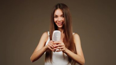 Evin içinde saç fırçalama tekniğini benzersiz bir stil aracıyla sergileyen kadın.